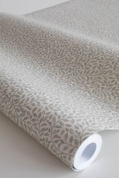 a white and grey wallpaper with leaves on the side, next to a roll of tape