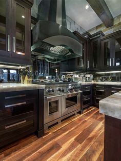 a large kitchen with black cabinets and stainless steel stove top oven in the center of the room