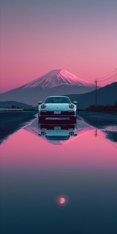 a car is parked in front of a mountain with the sun setting on it's horizon