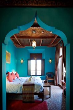 a bedroom with blue walls and red carpeted flooring is seen through an archway