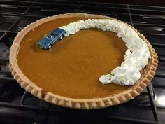 a pumpkin pie with a blue car on top and whipped cream in the middle, sitting on an oven rack