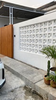 a white car parked in front of a house next to a wooden door and fence