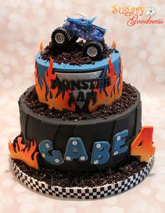 a three tiered cake with monster trucks on top