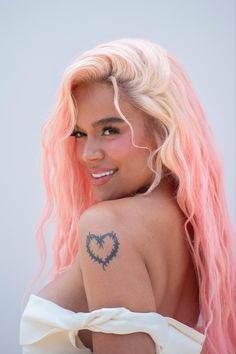 a woman with pink hair and tattoos on her back, smiling at the camera while wearing a white dress