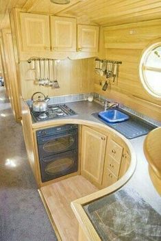 the interior of a small kitchen with wood paneling and stainless steel stove top oven