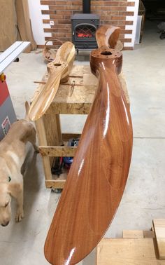 a wooden boat is being made in a shop with a dog standing next to it