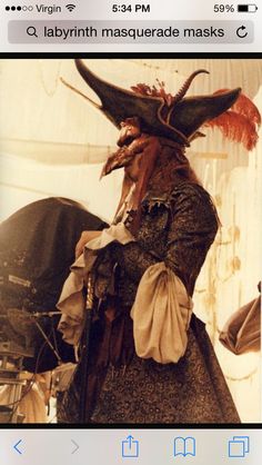 a man dressed up as a pirate with horns and feathers on his head, standing in front of a tent