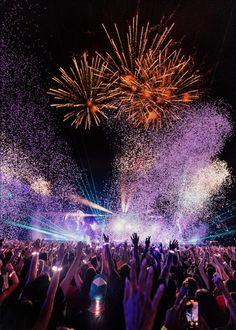 fireworks and confetti in the air at a concert with people holding their hands up