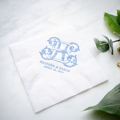 the monogrammed napkin is next to some green leaves and a gold ring on it