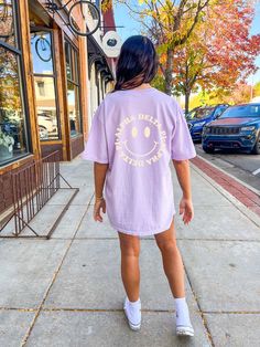 a woman is walking down the sidewalk with her back to the camera while wearing a purple shirt