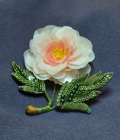 a pink flower sitting on top of a green leafy broochle with leaves