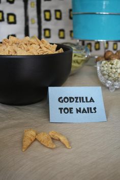 a table topped with a bowl of food and a sign that says godzilla toe nails