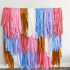 colorful streamers hanging on the wall in front of a white wall with wood flooring