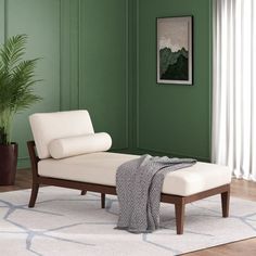 a white chaise lounge chair sitting on top of a wooden floor next to a potted plant