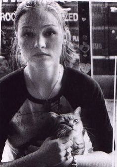 a woman sitting at a table holding a cat