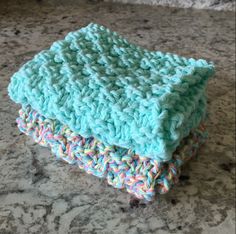 two crocheted dishcloths sitting on top of a granite counter next to each other