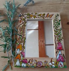 a mirror sitting on top of a wooden table next to a plant and some scissors