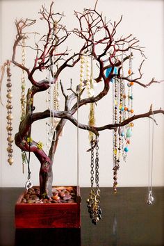 a bonsai tree with beads hanging from it's branches and chains attached to the trunk