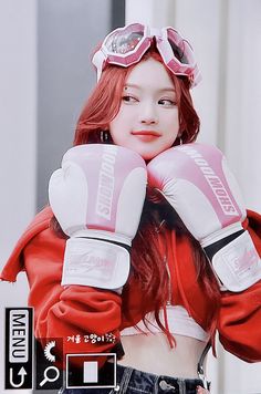 a girl with red hair wearing pink boxing gloves and a pair of goggles on her head