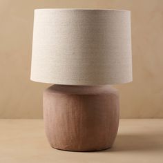a wooden table lamp sitting on top of a table next to a white lampshade