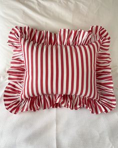 a red and white striped pillow sitting on top of a bed