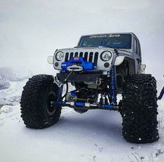 a jeep with four wheels is parked in the snow on top of a snowy hill