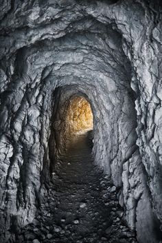 a tunnel in the ice with light at the end and snow on the ground inside