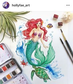 a drawing of a mermaid sitting on top of a table next to watercolor paints