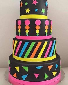 a three tiered cake decorated with neon colors and stars on the top is shown