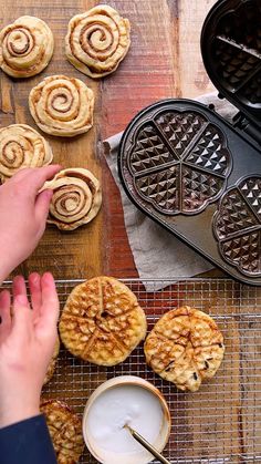 a person reaching for some food on top of a wooden table with waffles