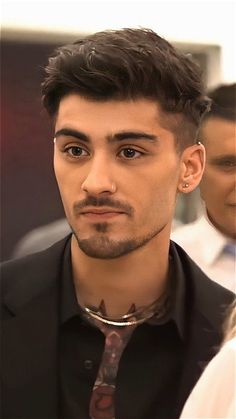 a close up of a person wearing a neck tie and black shirt with collar ring