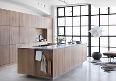 a kitchen with wooden cabinets and an island in front of a large window that looks out onto the outdoors