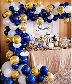 a balloon arch with gold and blue balloons on the top, along with other decorations