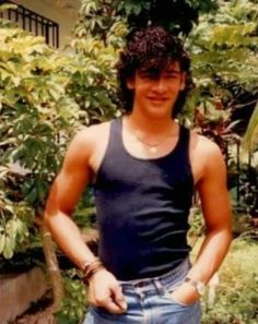 a young man standing in front of some bushes