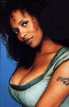 an image of a woman with tattoos on her arm and chest posing for the camera