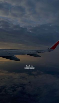 the wing of an airplane as it flies through the sky with clouds in the background