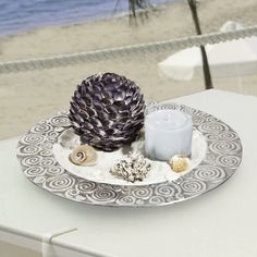 a white table topped with a plate covered in seashells and a lit candle