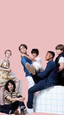 a group of young men sitting on top of a white bench in front of a pink wall