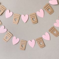 some paper hearts are hanging on a string with clothes pins in the shape of coffee cups