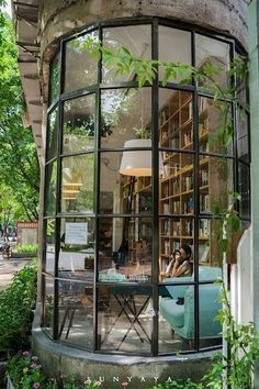 the inside of a round building with lots of bookshelves and plants in it