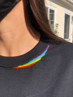 a close up of a person wearing a black shirt with a rainbow painted on it