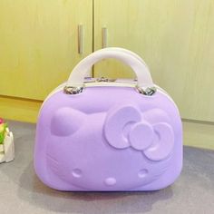 a purple hello kitty purse sitting on top of a counter next to a small cake