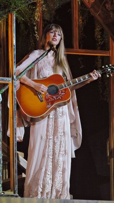 a woman in a white dress holding a guitar