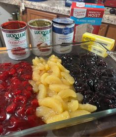 an assortment of fruit and cheeses in a glass dish on a counter top with condiments