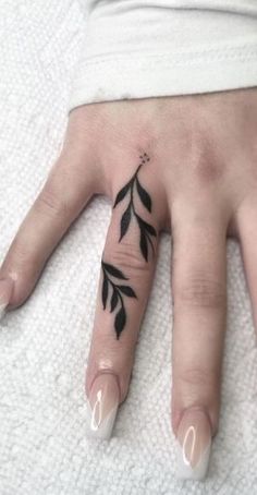 a woman's hand with black leaves on it