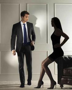 a man in a suit standing next to a woman wearing tights and high heels