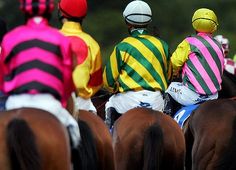 three jockeys are sitting on their horses as they ride down the track together,