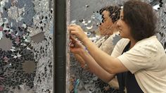 a woman is looking at the reflection of another person in a mirror that looks like he's holding something