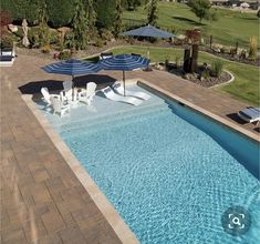 an image of a pool with chairs and umbrellas next to the swimming pool that is empty