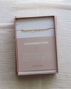 a pink box with a gold bracelet in it on top of a white bed sheet